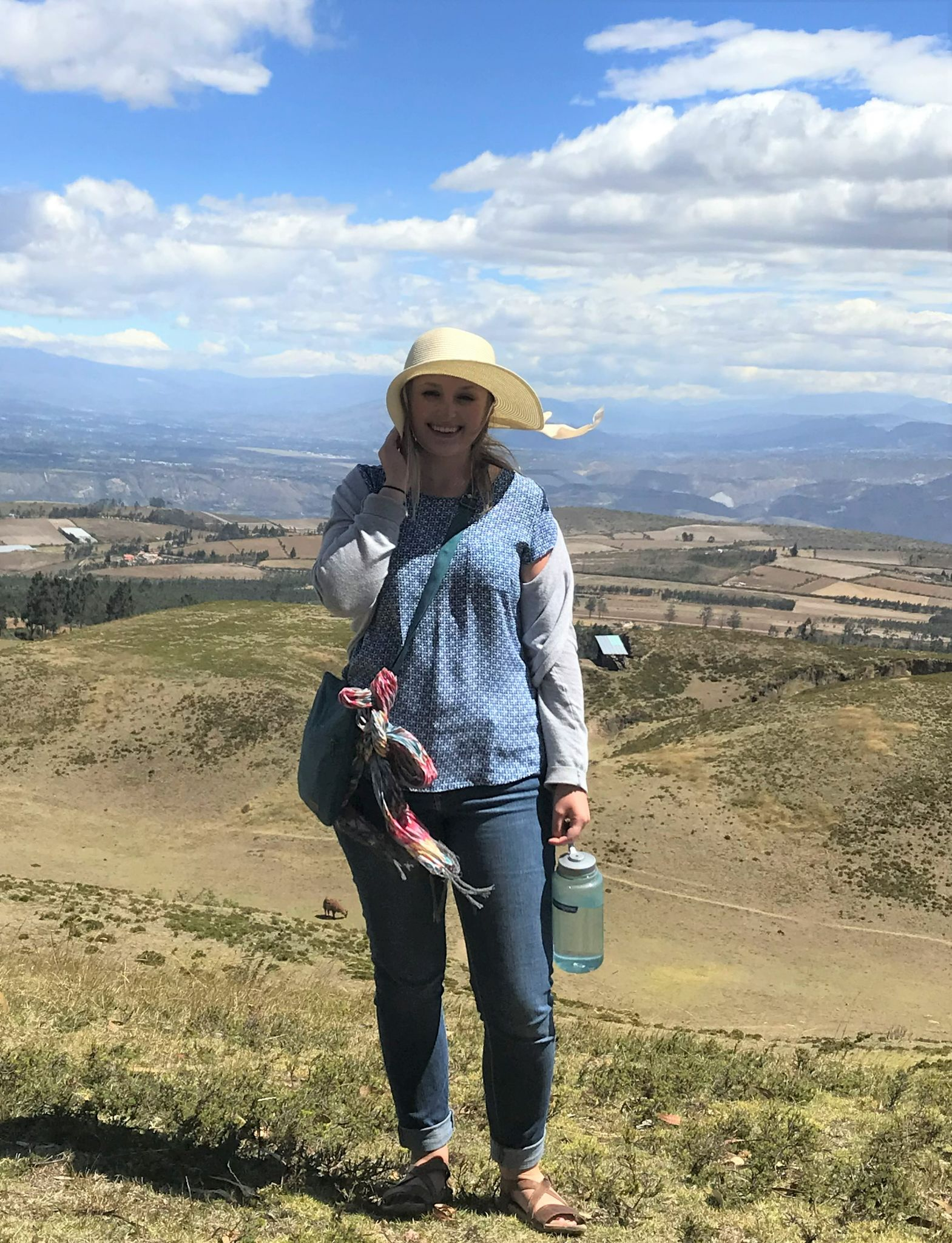 Audra Gaikowski standing on top of a hill overlooking fields.